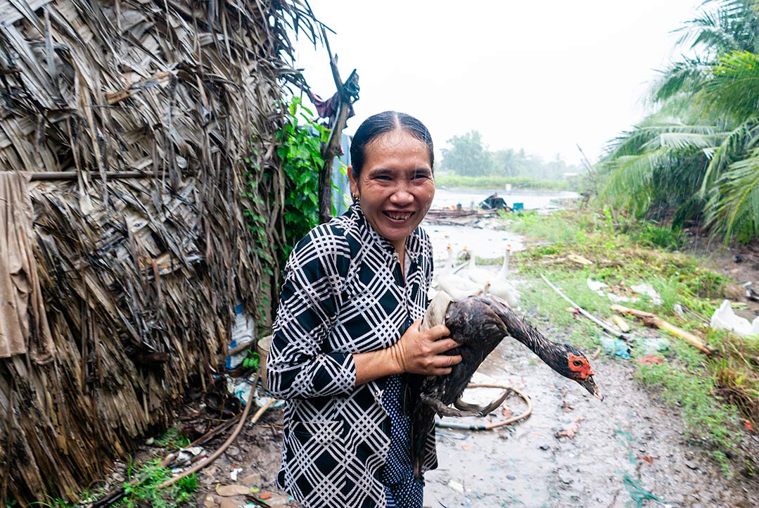 A woman laughs holding her duck in the rain