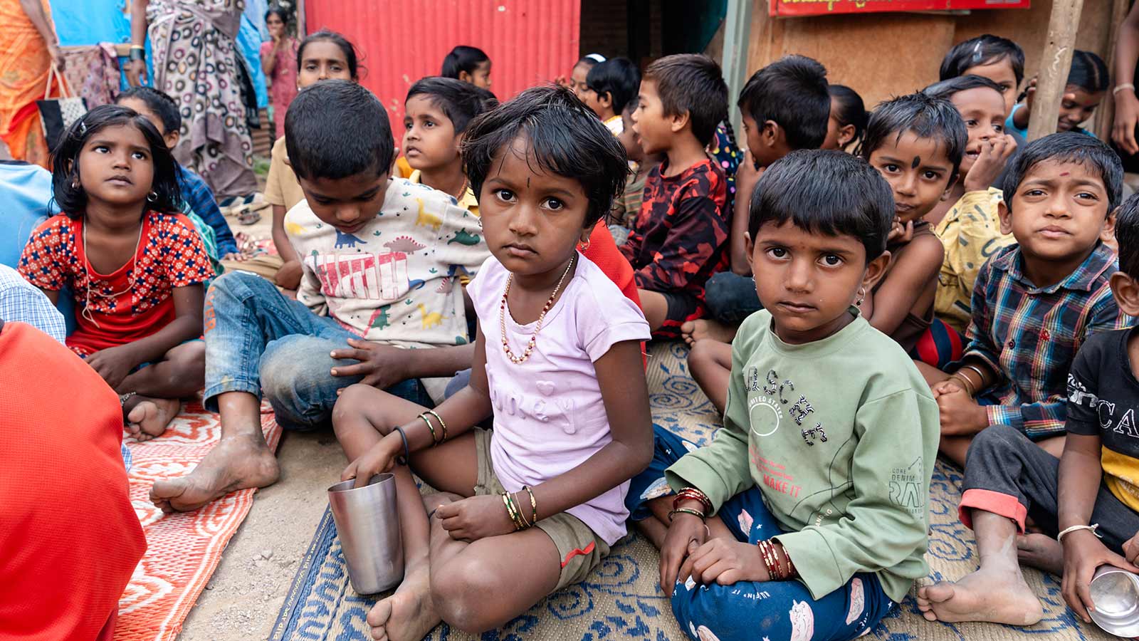 children living in a migrant camp wait for emergency food