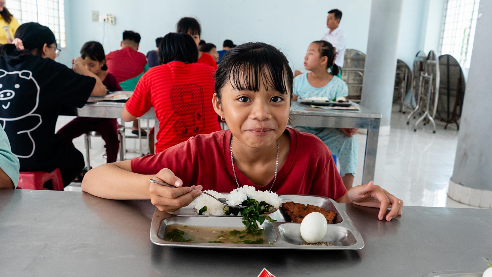 a young girl at an orphanage in Vietnam eats her lunch