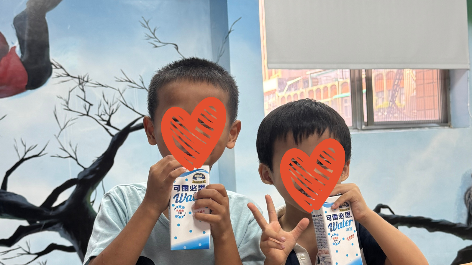 Two children drink water and smile at the camera.
