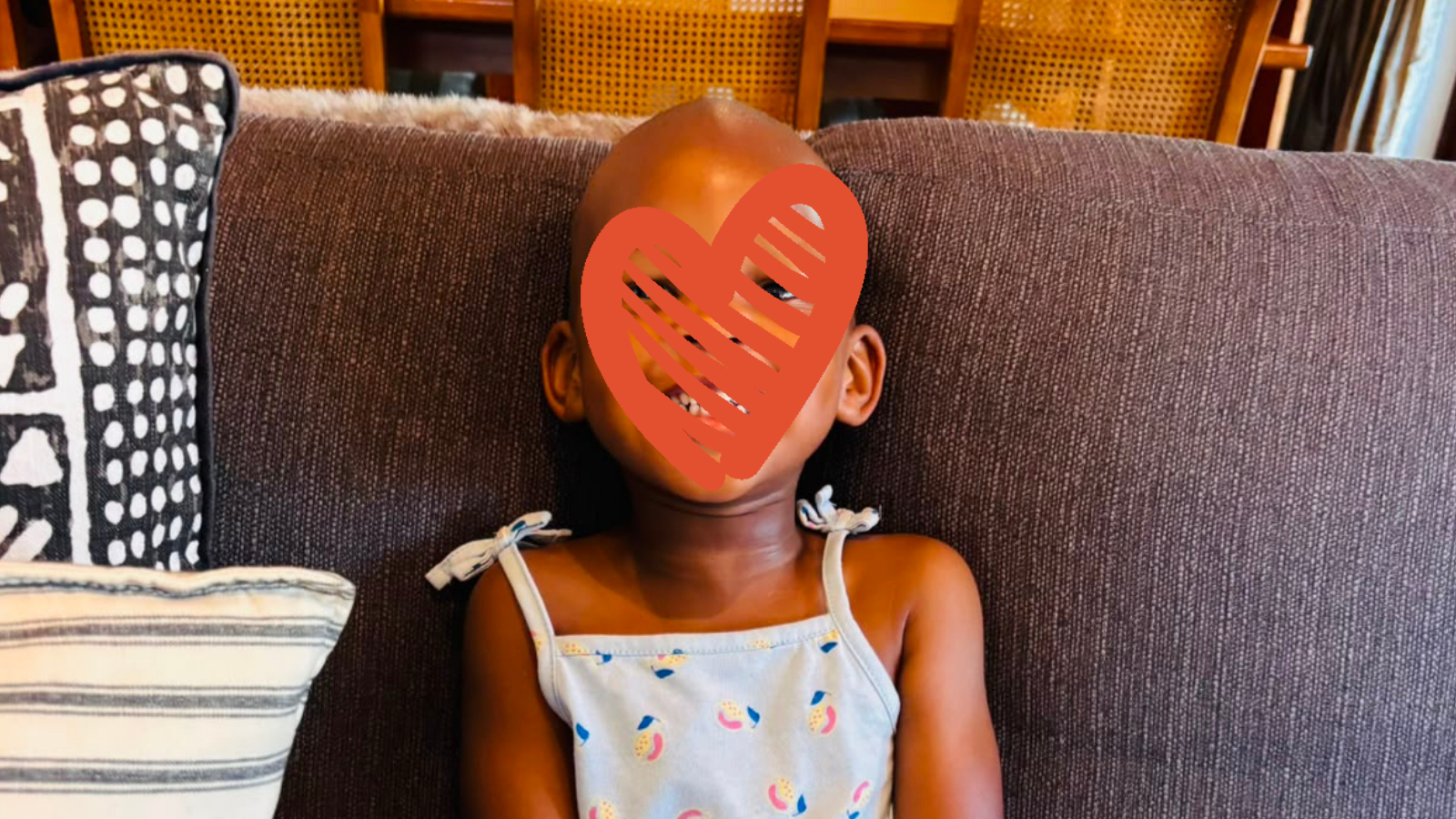 Child sits on couch and smiles at camera.