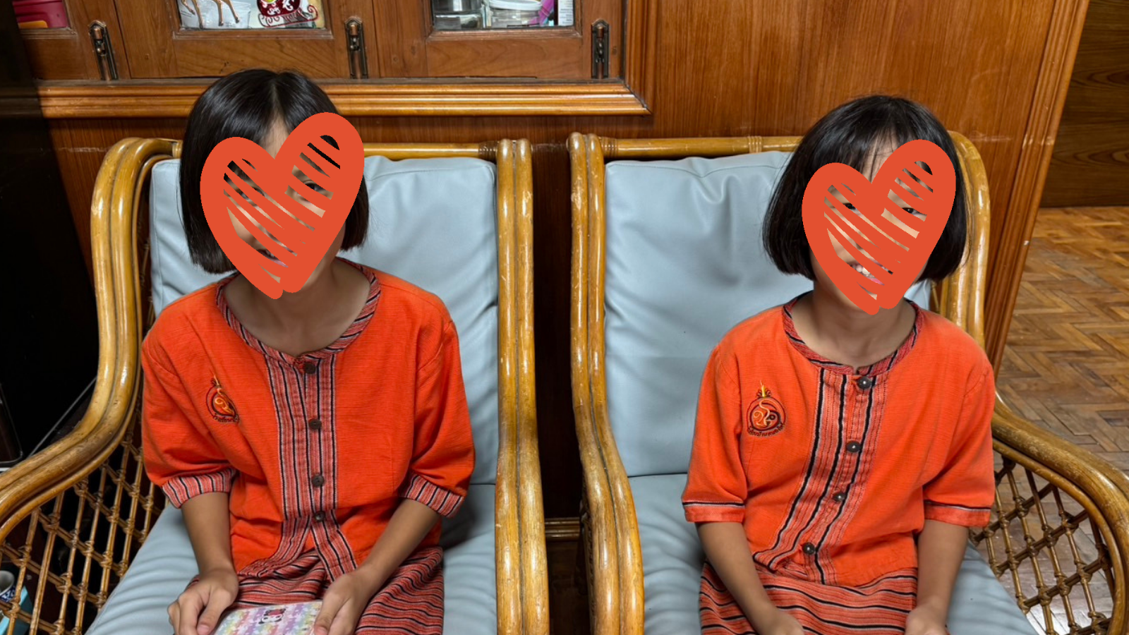 Two little girls sit on chairs and smile at the camera.