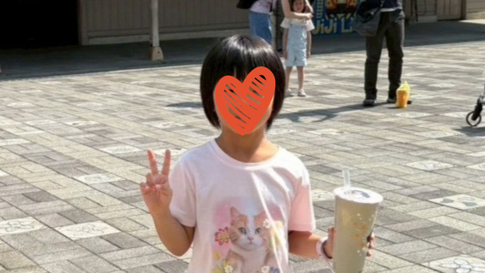 Child holds drink and smiles at camera.