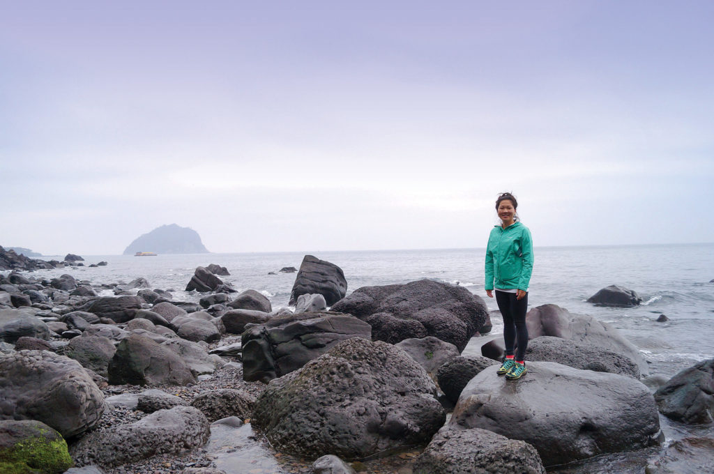 Cat standing on large rocks near water