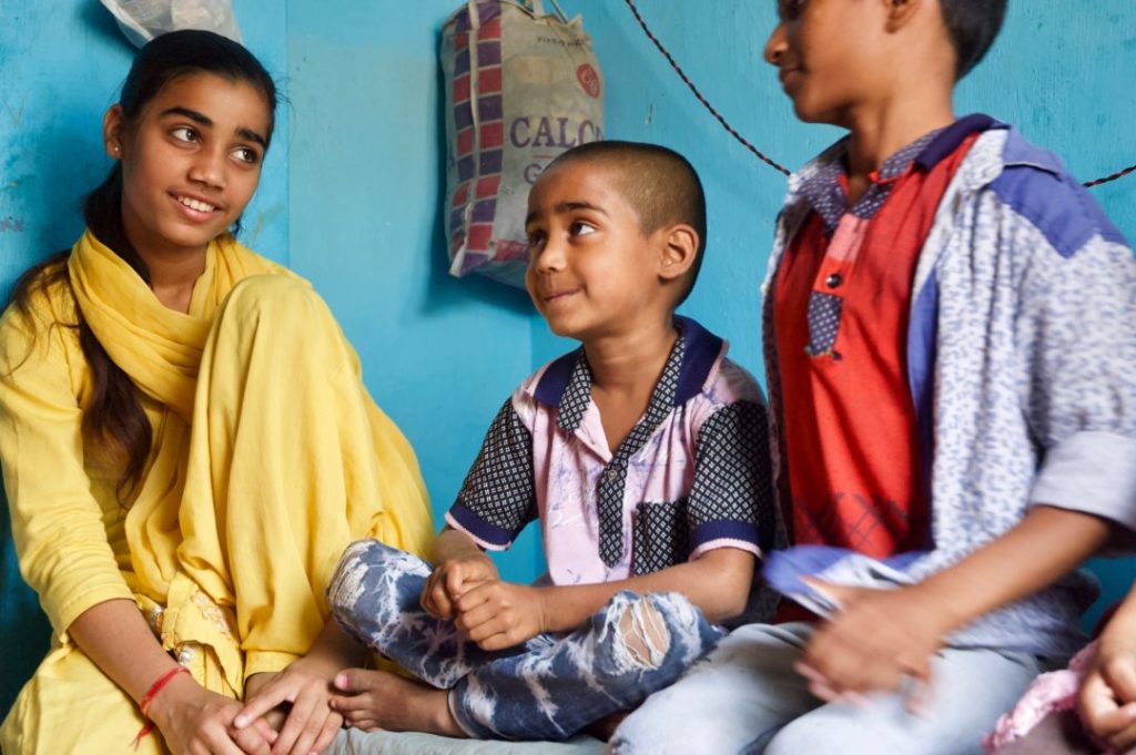Close-up of three of Shabnam's children sitting on bed looking at each other