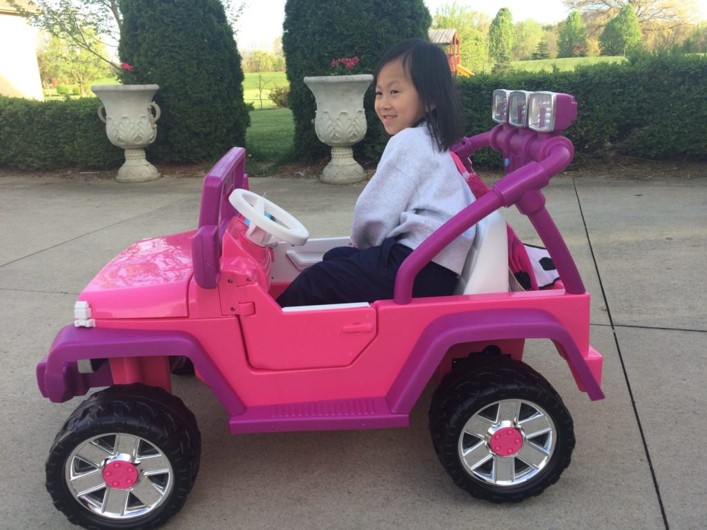Child sitting in a motorized child's Jeep
