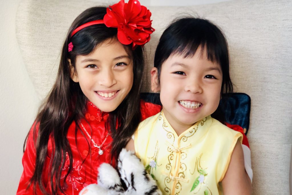 Two girls sitting together on a chair posing and smiling for the photo