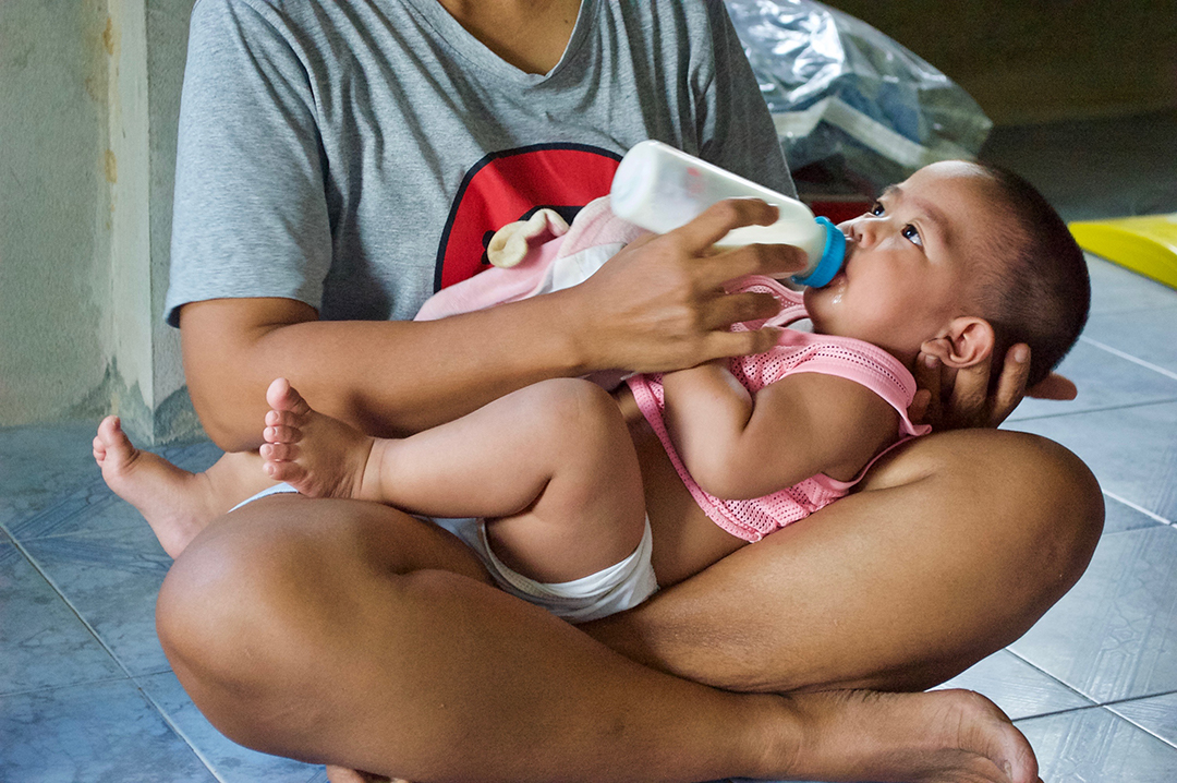 a caregiver feeds her child through Gifts of Hope