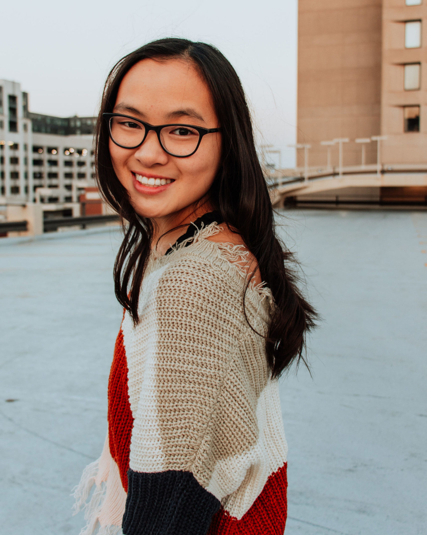 smiling girl looking over her shoulder wearing glasses
