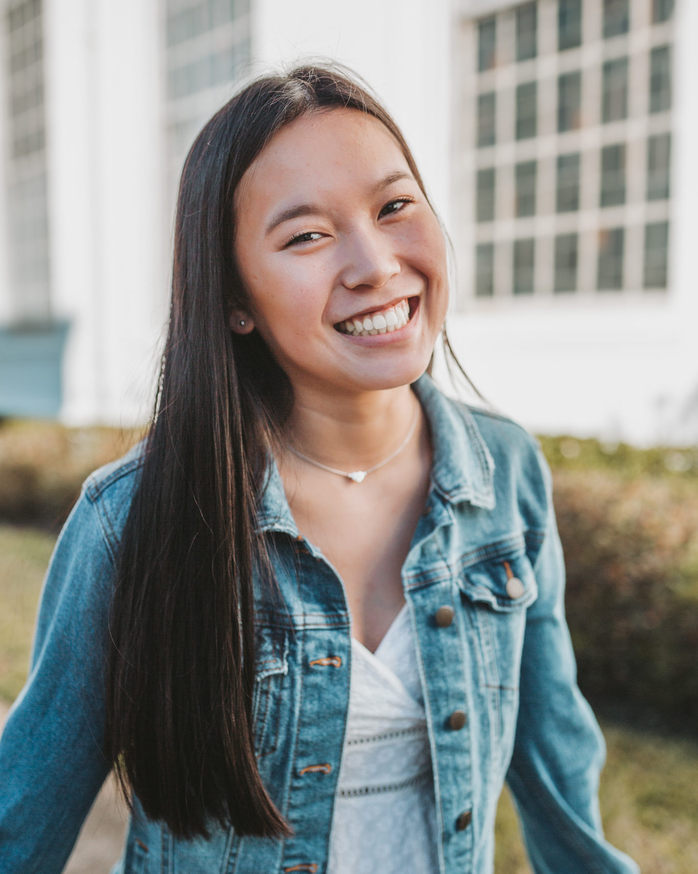 smiling girl wearing white dress and denim jacket