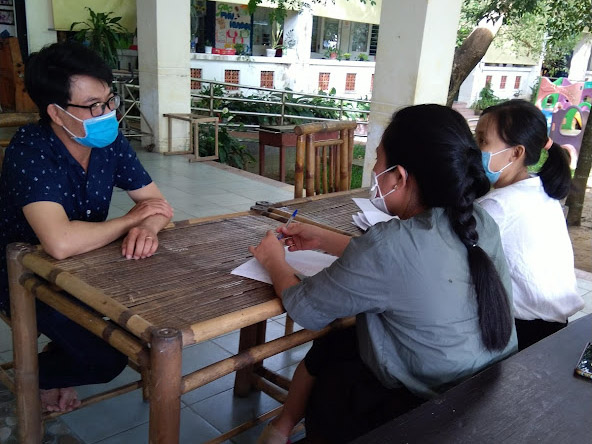 three people sitting at a table with masks