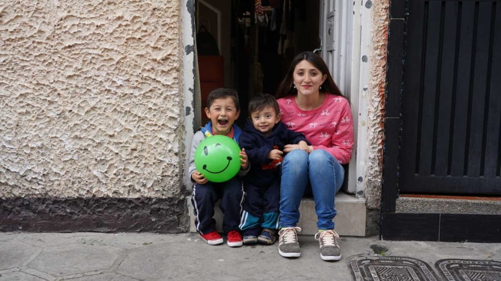 three Colombian children sitting in doorway