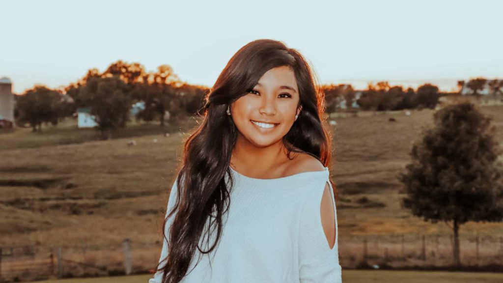 girl smiling in front of field 