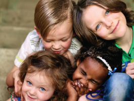 Closeup of group of four children's faces smiling laughing and posing for camera