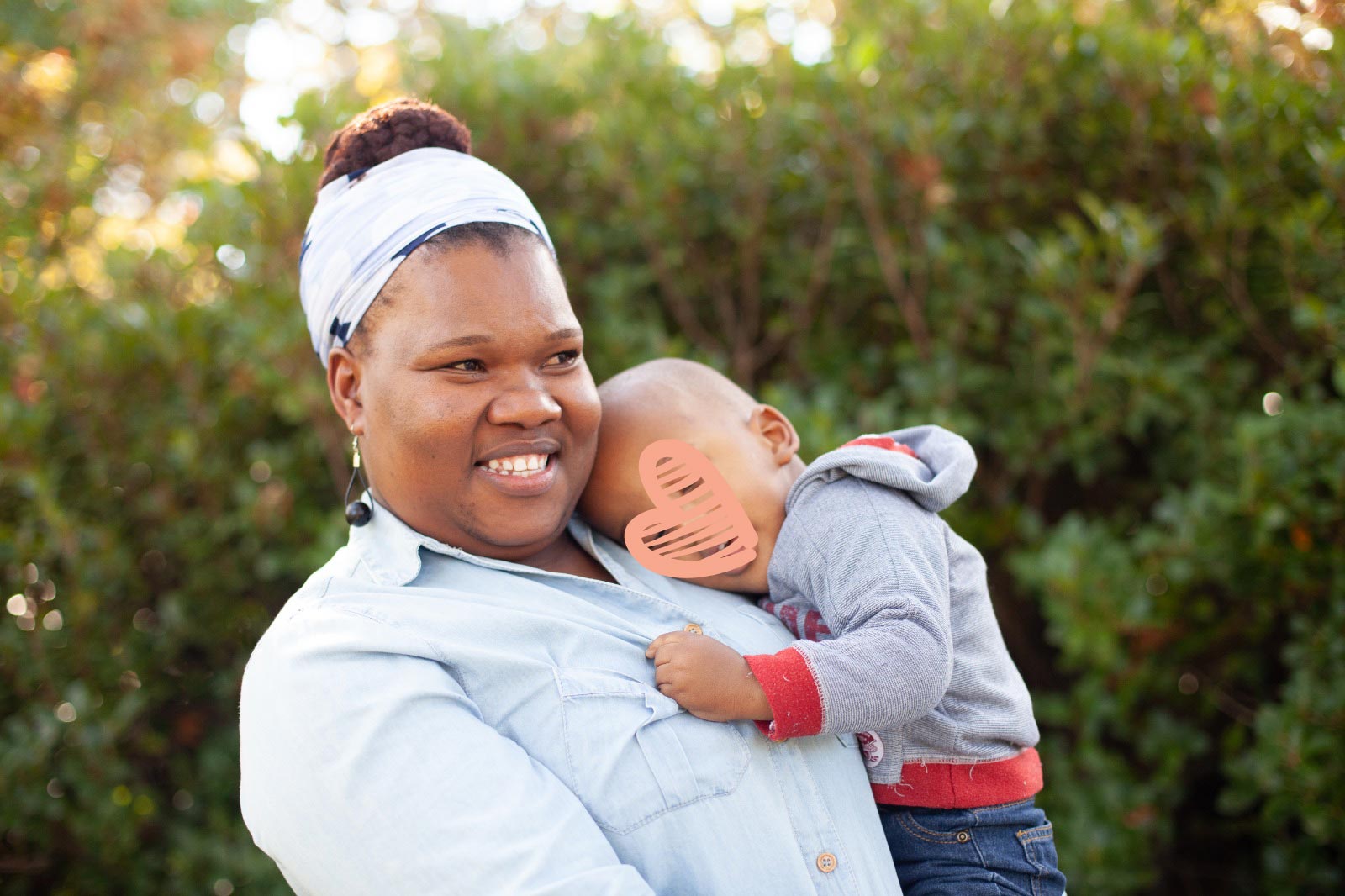 smiling woman holding small child with heart graphic over child's face