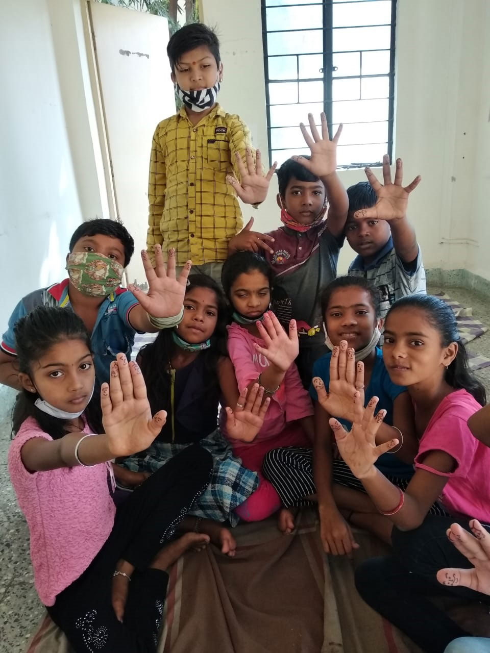 Children in India holding up hands with different facial expressions on their fingers.