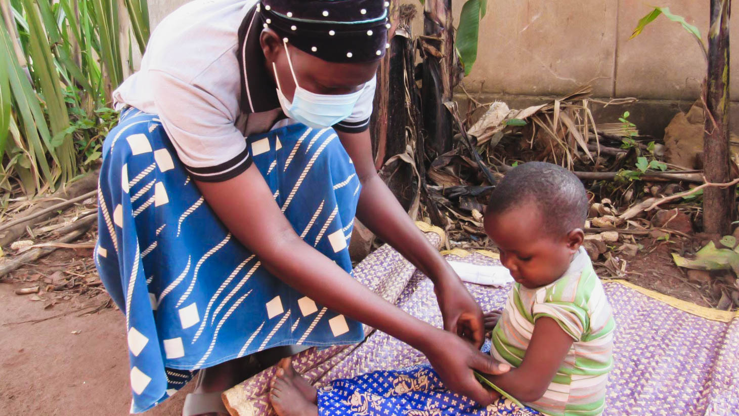 woman measuring baby's arm to check status of malnutrition