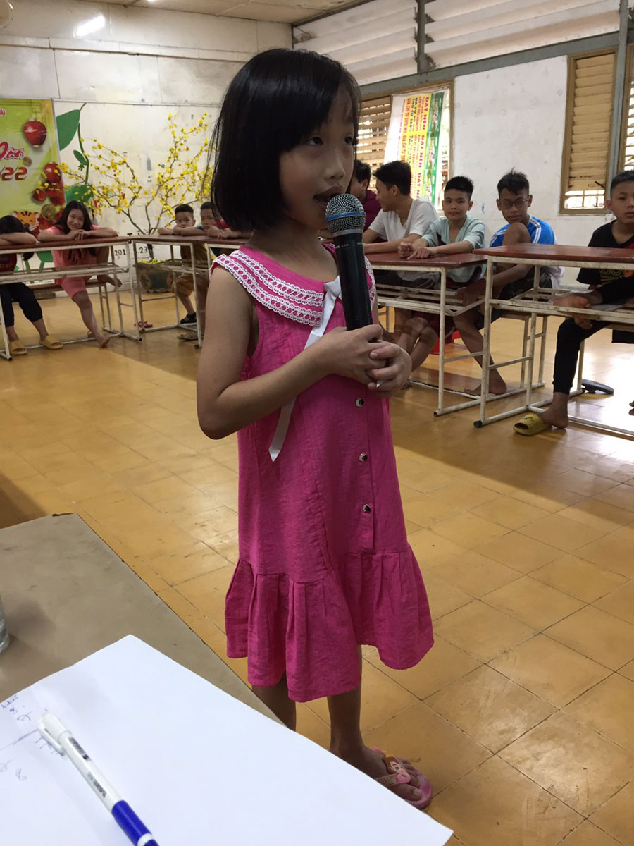 little girl in pink dress singing into a microphone