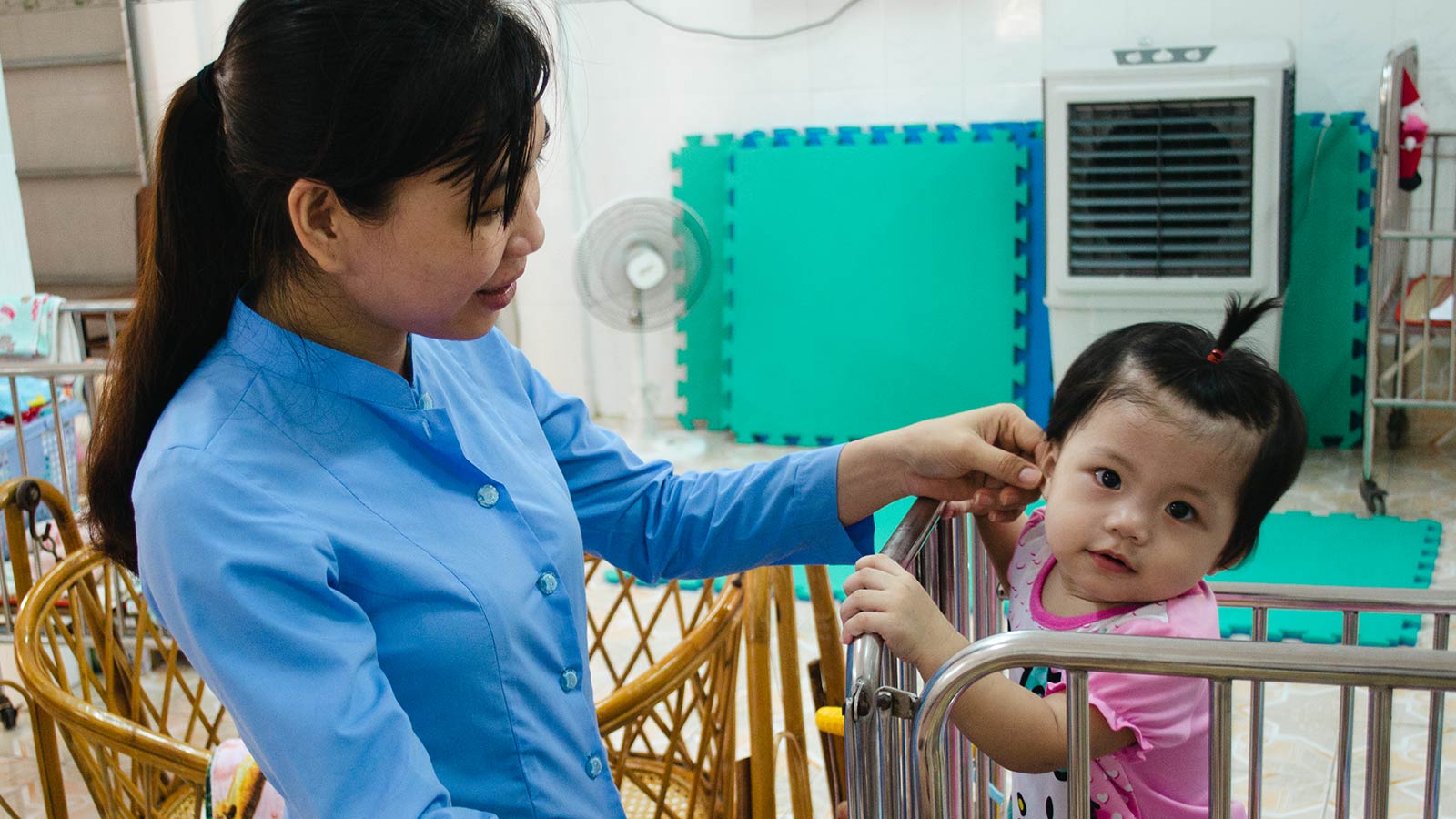 caregiver smiling down at baby living in orphanage