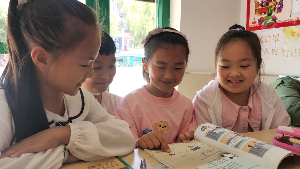 A group of young girls sitting in class looking at a school book