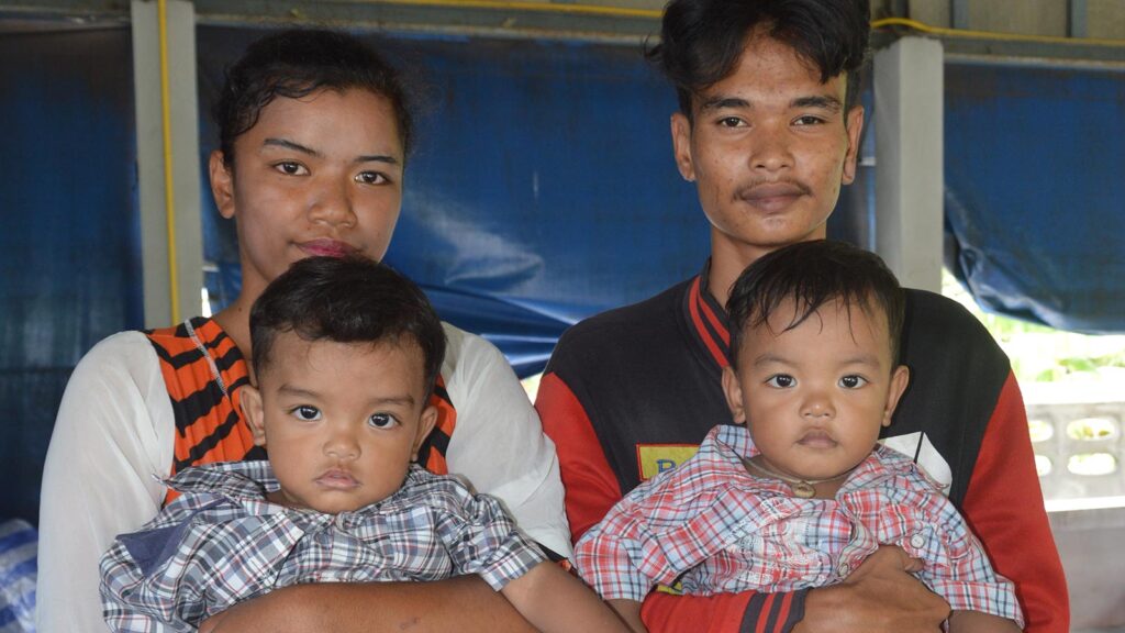 Teen parents in Thailand holding sponsored twin sons