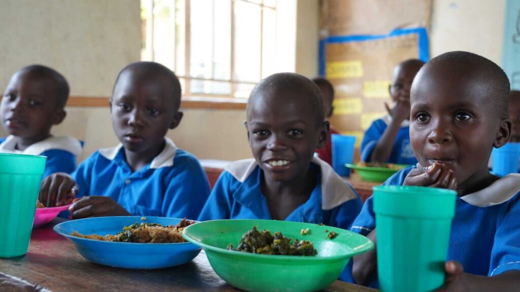 Children sitting at school eating lunch together smiling at the camera