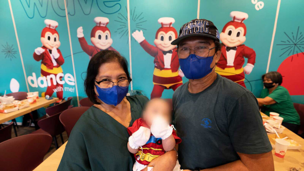 Foster parents in the Philippines hold a baby in at a Jollibee Christmas party
