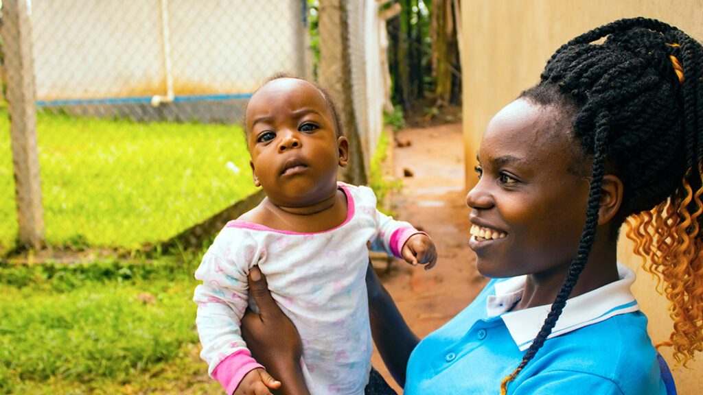 A mom in Uganda holds up her baby, smiling