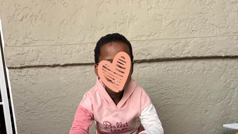 Little girl in a pink sweater sits at a table