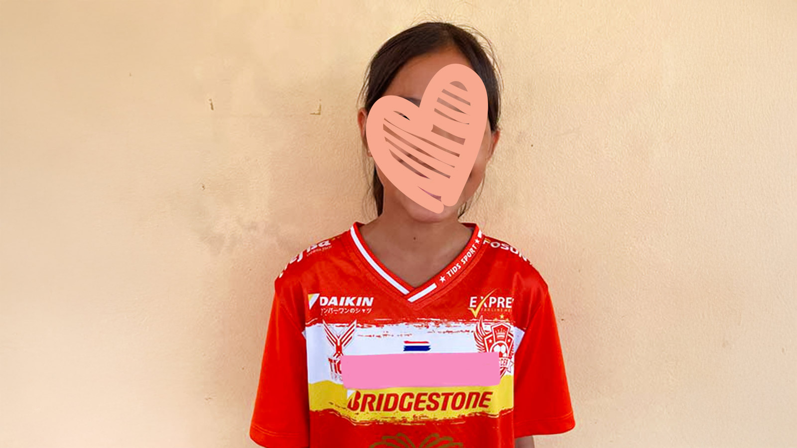 a girl stands against a wall, ready to be adopted