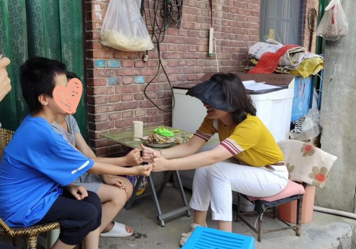 A social worker sits across from two children and interacts warmly with them