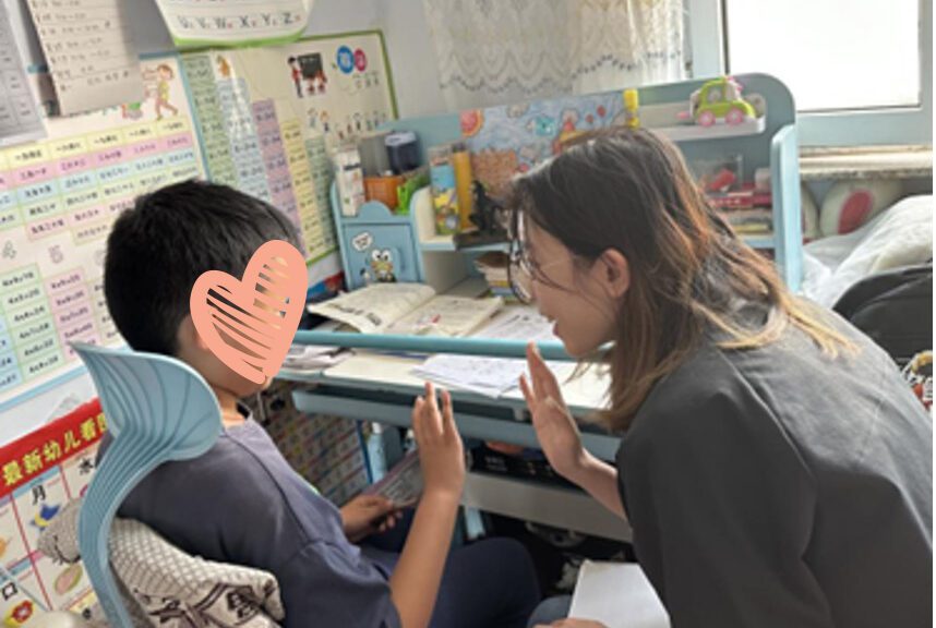Social worker gives a little boy sitting at a desk a high five