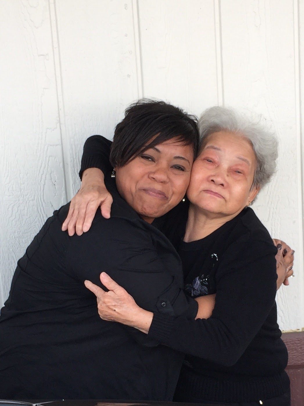 Mother and daughter hug and smile at the camera