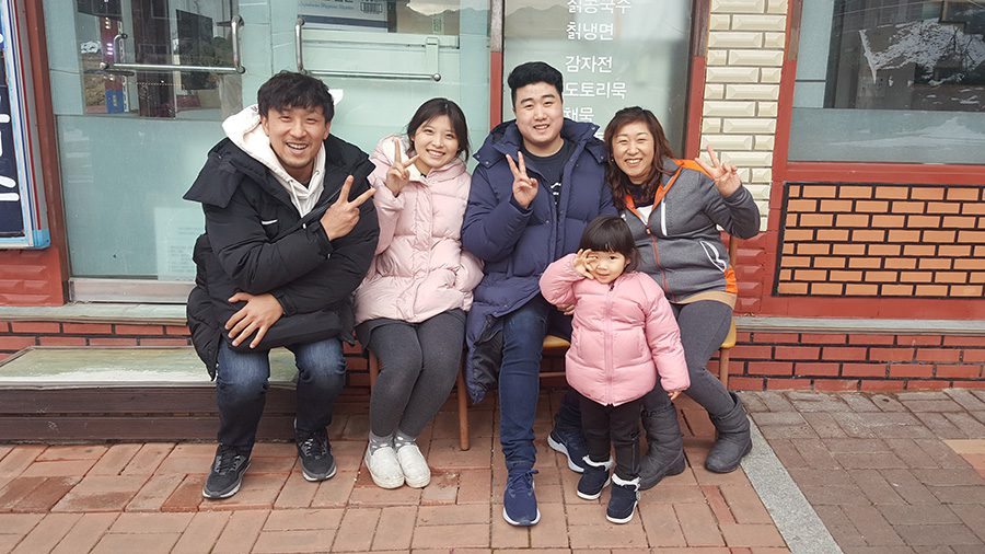 Group of people smile at camera and make peace sign