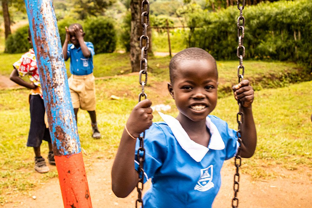 Little girl in school uniform swings and smiles