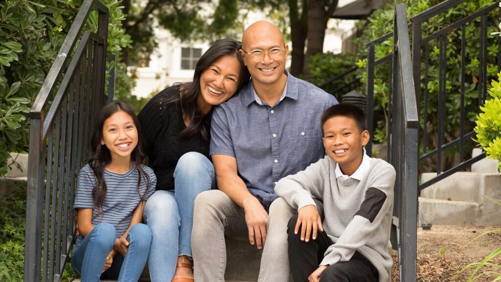portrait of happy family of four on their front steps