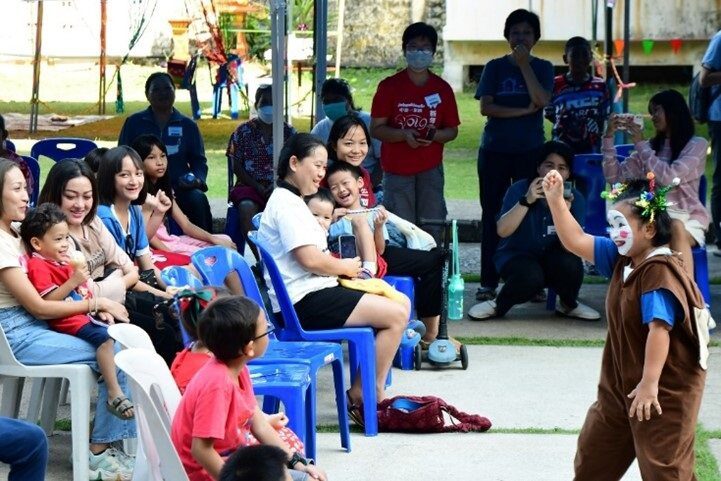 Group of seates people in Thailand have a celebration, laugh at a silly performer