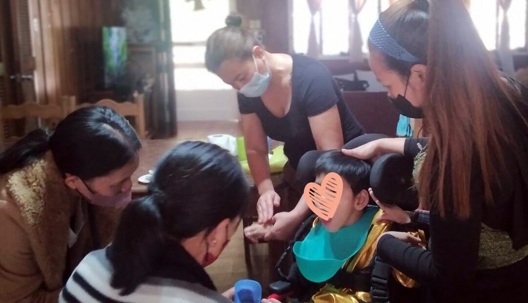 Caregivers come around a boy in a wheelchair