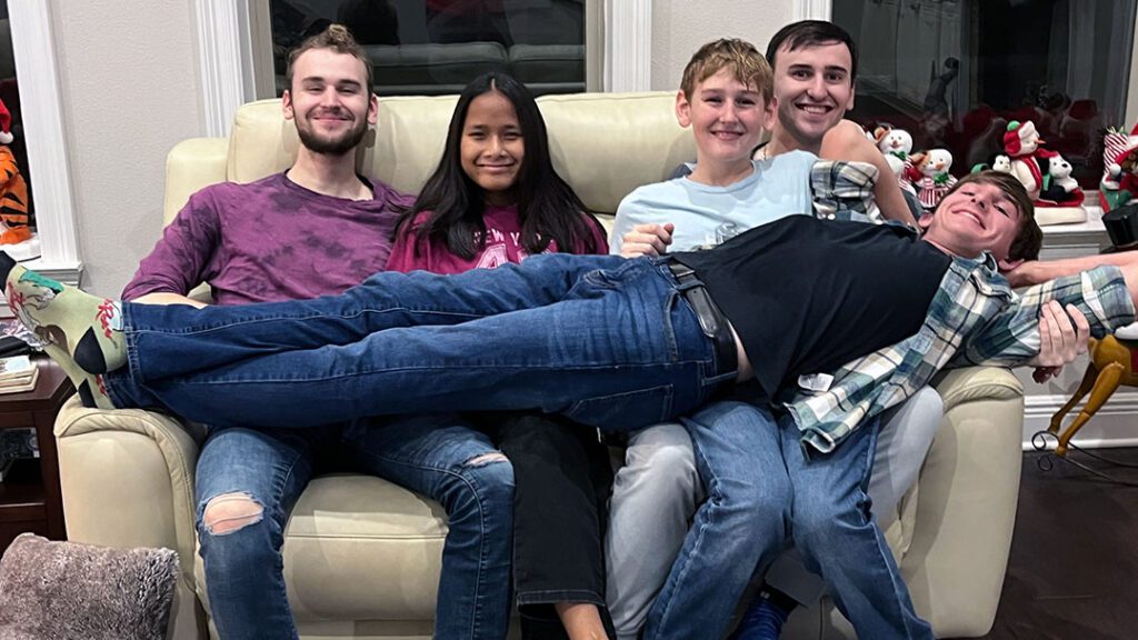 a brother lays on top of his siblings for a goofy photo