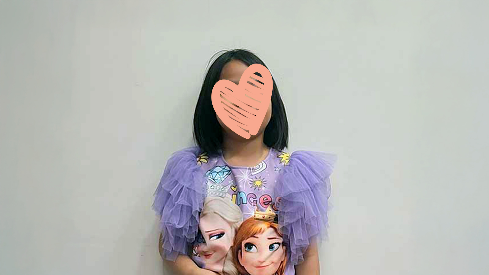 a girl in a purple princess dress smiles with a heart over her face