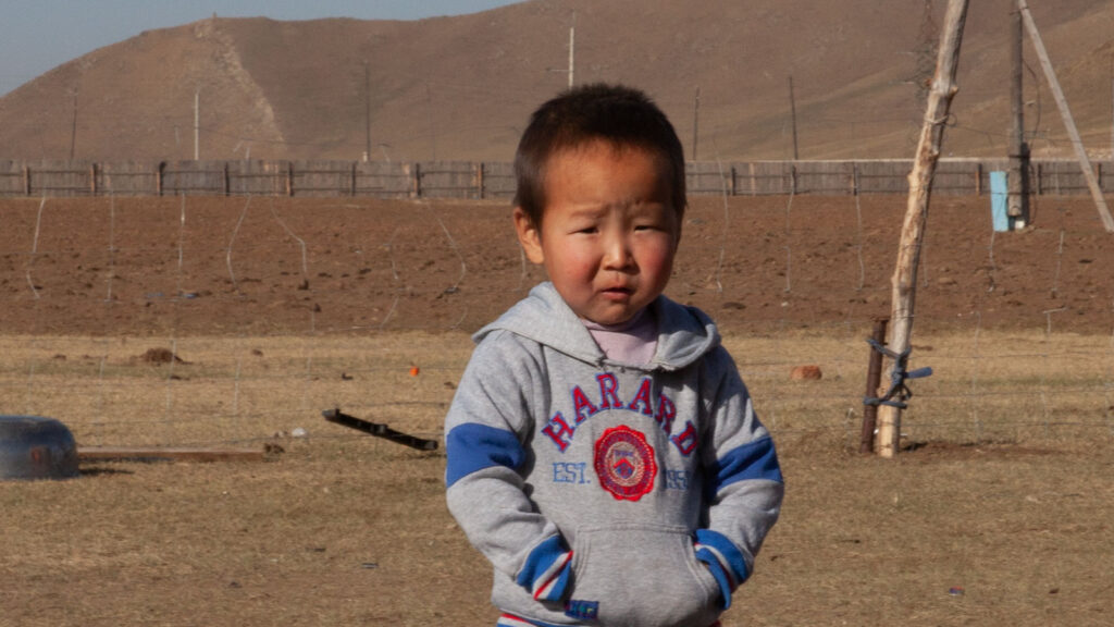 little boy standing outside in Mongolia in only a sweatshirt