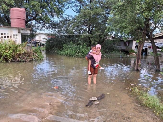 Mom carries child during floods in Thailand, Holt-supported programs worldwide 