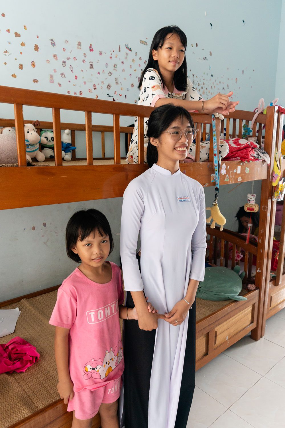 Girls growing up in an orphanage in Vietnam stand beside their bunkbeds.