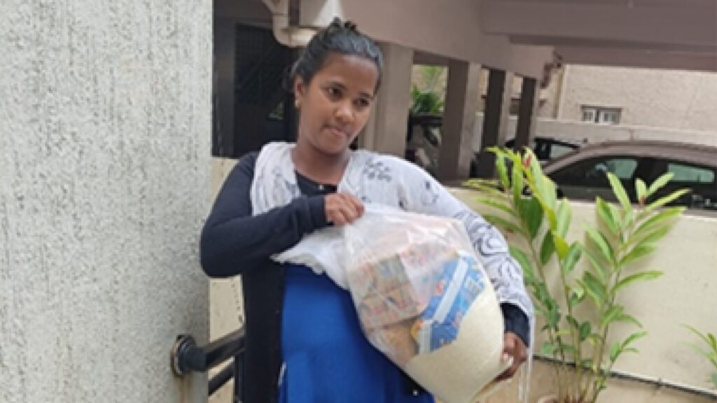 Holt sponsors and donors offer food assistance to a young mother in India, who holds an emergency food pack