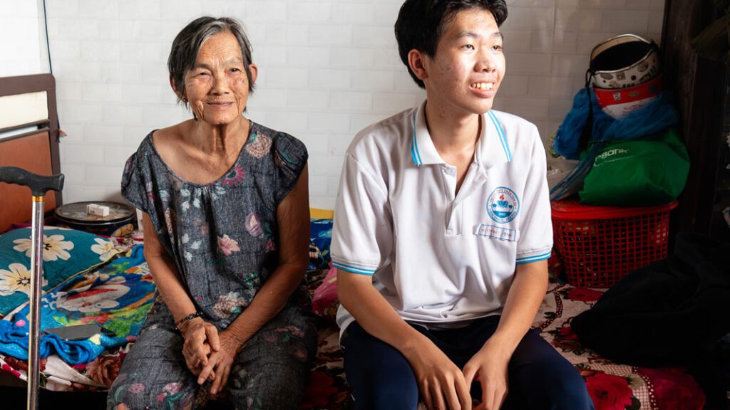 zoomed in view of grandmother and grandson sitting on grandmother's bed