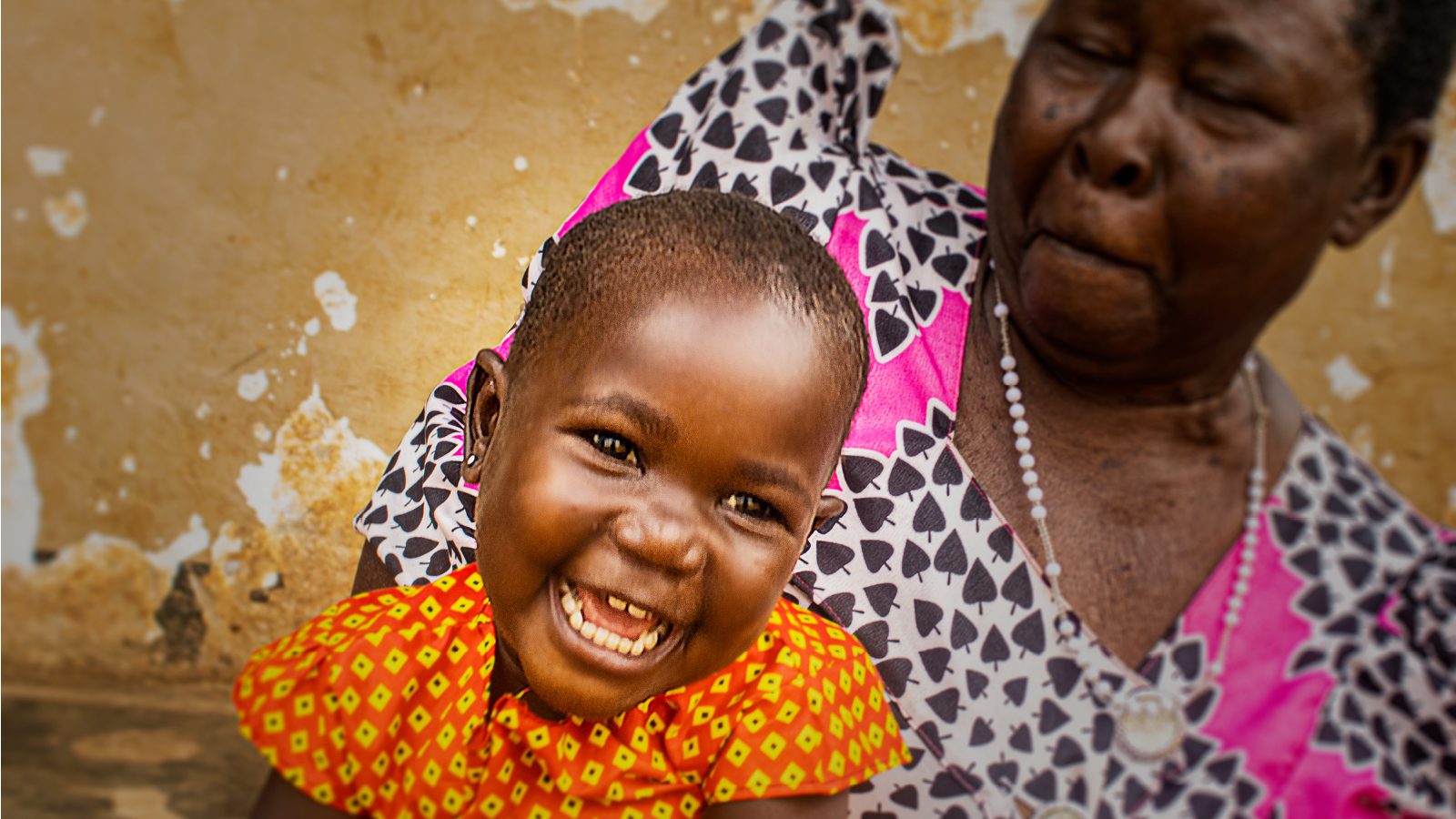 Achen with her grandmother, smiling, after receiving food assistance in Uganda