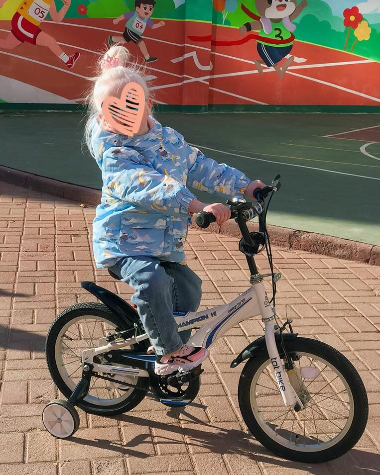 a little girl rides a bike in china with a heart over her face