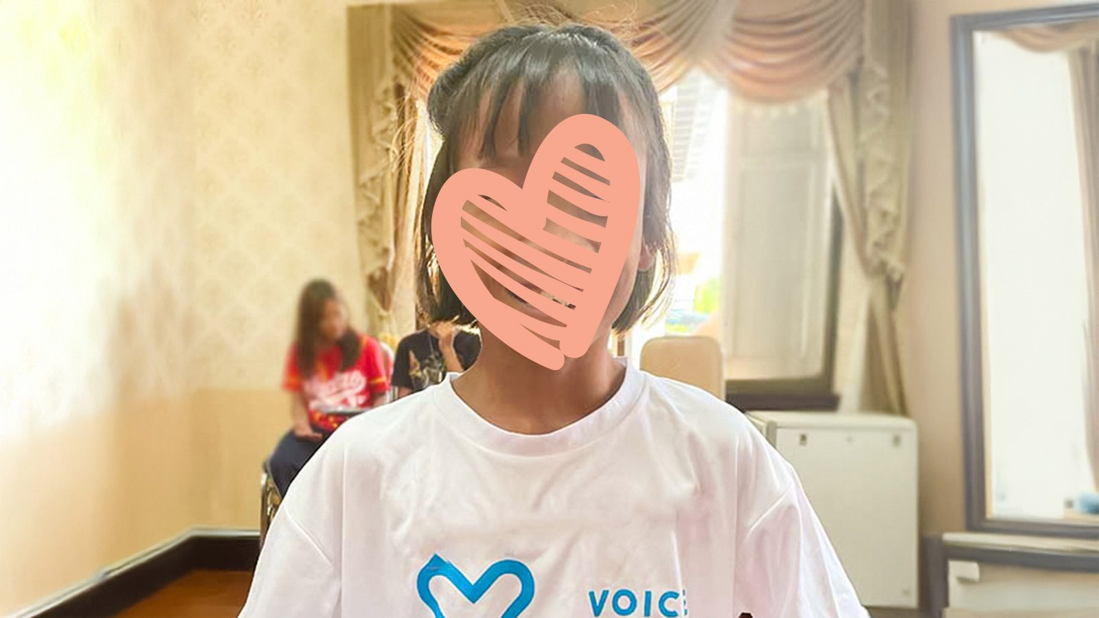 A child with a heart over her face is ready for adoption