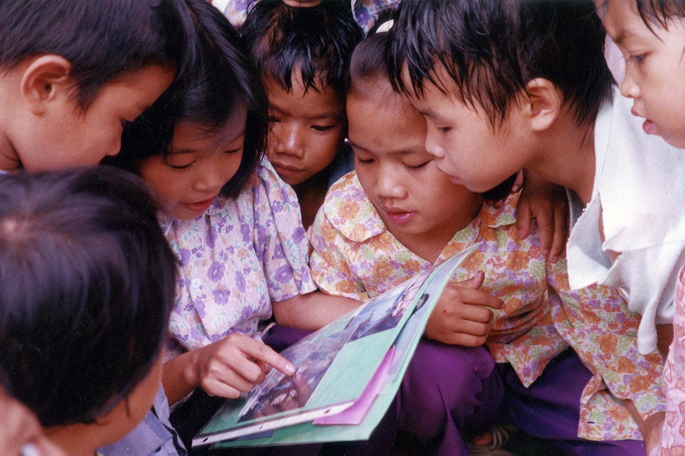 children gather around a photo album from an adoptive family in the U.S. in 1975.