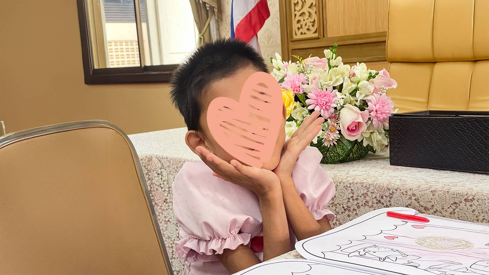 A waiting child with a heart over her face poses for the photo